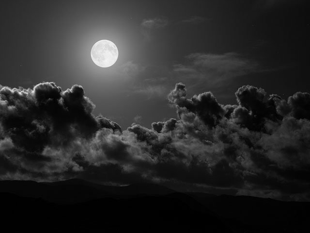 Una imagen tomada de la web de la luna llena sobre un manto de nubes.